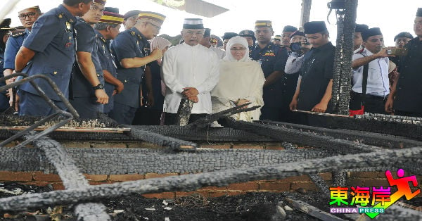 消拯局总监拿督莫哈末韩丹（左4）向元首伉俪解说失火现场情况。