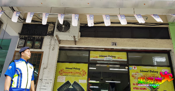 关丹市议会执法人员检视商店前仍悬挂的逊色小国旗。