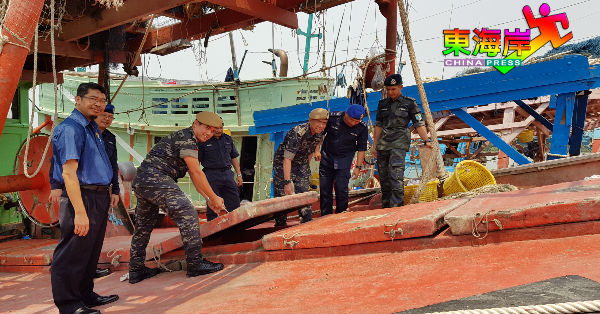 菲索（左5）等人登上非法入境作业的越南渔船后，检视渔船冰箱。