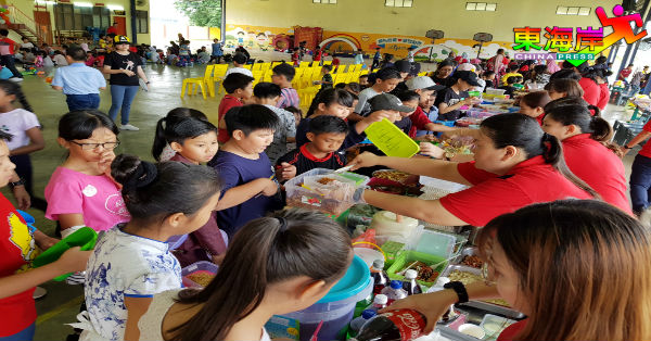 学生们在老师的帮助下，有秩序领取儿童节美食。