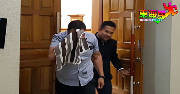 慕哈末拉依央（左）否认贪污罪名后，被反贪会官员押离法庭。
