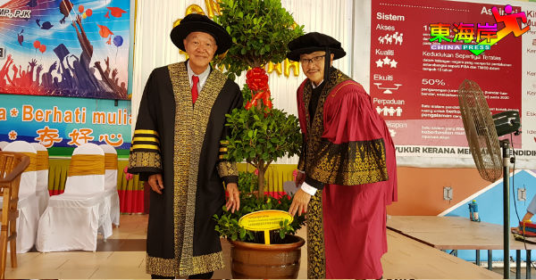 朱源安（左）代表董家协及校友会移交榕树予学校，由陈国辉接领。