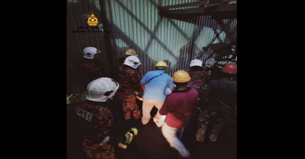 消拯员在油棕厂员工协助下，合力将卡在机器的尸体拉出。