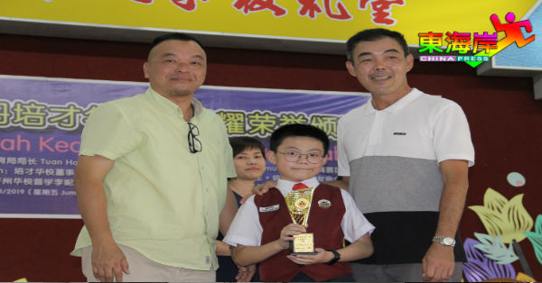 汤侍城（左）颁发奖杯予全彭华小华语演讲比赛冠军陈亮佑，右为家长陈思明。