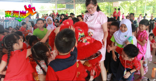 学前班学生对舞狮表演感到新奇，纷纷伸手触摸。