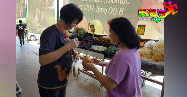 罗异圆（左）协助客户挑选中国进口莲藕。