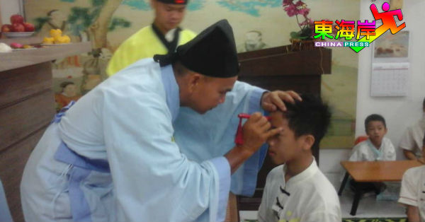 李国雄老师在拜师礼中为新生叶俊康点朱砂，以示开启学生智慧。
