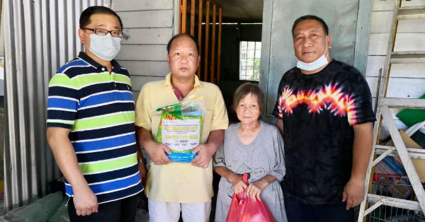  陈光明（左）与陈俊贤（左4）移交物资予华裔贫困家庭。