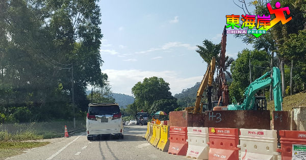 关丹东姑慕哈末路段因挖掘工程在施工中，来往车辆在交通指挥员协助下轮流穿过工程地。