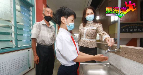 关丹公民华校校长丘月清（右起）及董事长蔡柏基指引学生勤洗手，保持卫生。