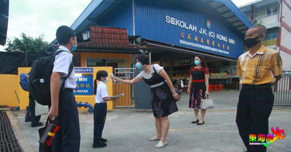 公民华校的老师在门口前，为每位进入学校的学生，测量体温。蔡柏基（右起）及丘月清也在场视察。