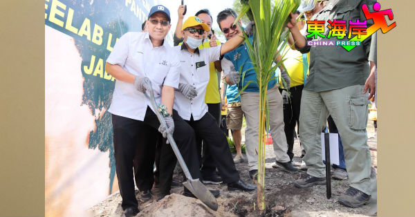 法卡鲁丁（左）在众人陪同下，为丹绒巴都海滩防海蚀计划植下椰树苗。