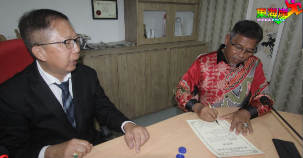 哈纳菲亚末（右）在刘星达蝉联甘马挽中华大会堂主席职宣誓证书上署名见证。
