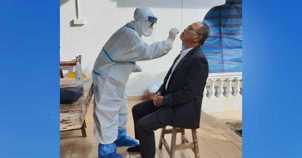 大臣旺罗斯里（右）出门上班前，接受医务人员进行病毒拭子检测。