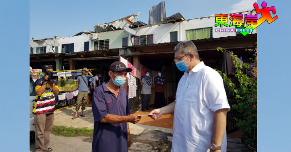 赛夫丁（右）在英迪拉马哥打第2区巡视住家遭受风灾情况时，移交援助金予灾民。