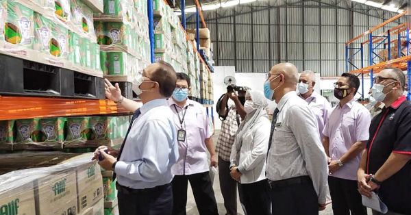 旺罗斯迪（左）聆听达鲁玛慕超市物资中心负责人汇报分配赈灾物资工作进度。