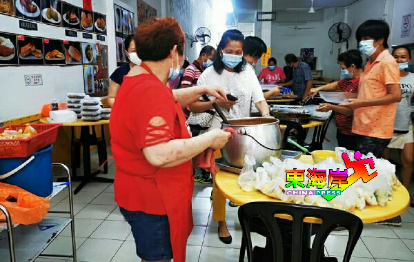 饶玉娇（左）与同处一店的食档业者，精心准备素食餐派发给公众。