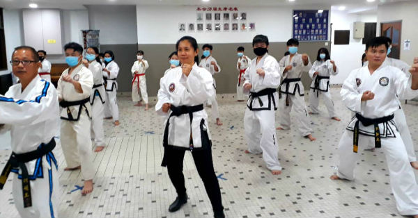 郑春子（前中）在洪祺华、曾昭荻带领下，与跆拳道学员一起练习。