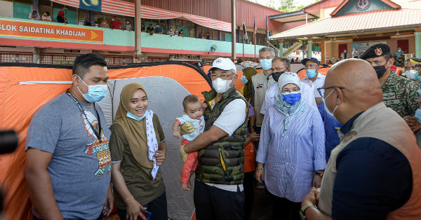 元首阿都拉（左3起）及元首后东姑阿兹札，探访马兰国中疏散中心灾民时，不忘逗弄灾民宝宝。