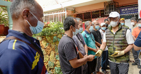 元首阿都拉（右）在马兰国中水灾疏散中心，派发援助金给灾民。