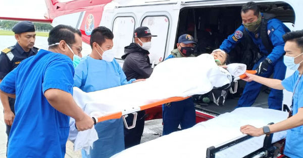 医务人员及飞行员合力将脊椎骨折及可能头骨裂的女伤者抬下直升机。