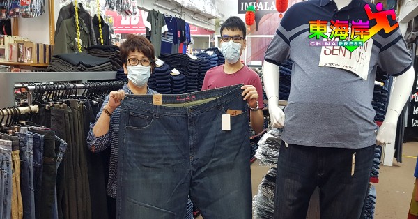 莫美珠（左）及李健豪展示店中的最特大号“60码”牛仔裤，可容下两个成年人。