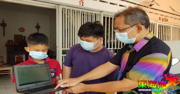 祖来迪（右）亲自指导梁家圣及梁健兴如何操作笔记型电脑上网课。