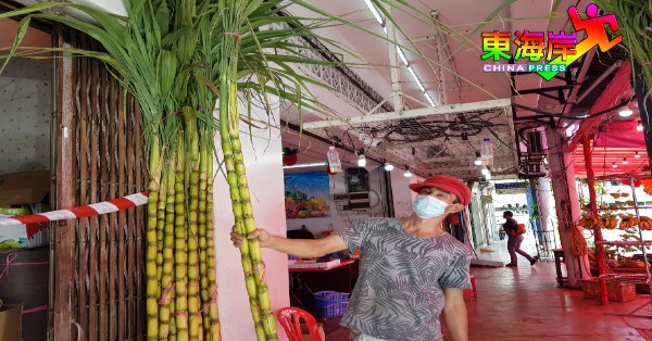 水果店员工将笔直的甘蔗摆放在店外，方便客户登门选购