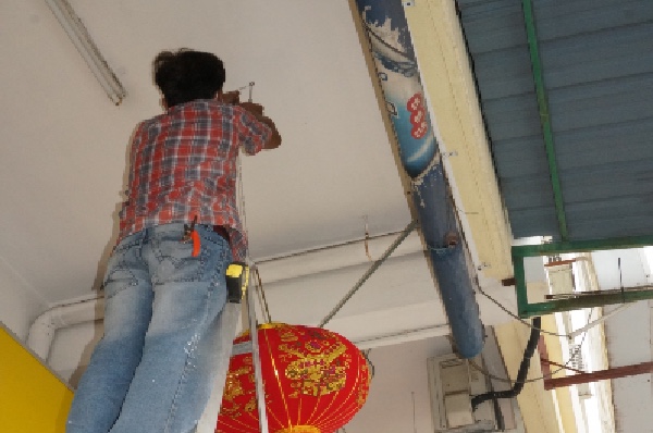 关丹社区关爱服务中心成员为商家，挂上红彤彤的灯笼。 