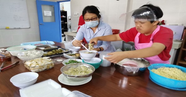 关丹同济会特殊孩童中心孩童在余秀芳（左）协助下，动手参与制作早餐。