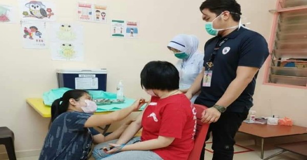医护人员在家长陪同下，为学生接种疫苗。