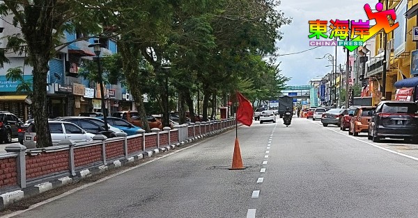 关丹大街路中央出现大坑后，民众自行置放警示三角椎及插上红旗。