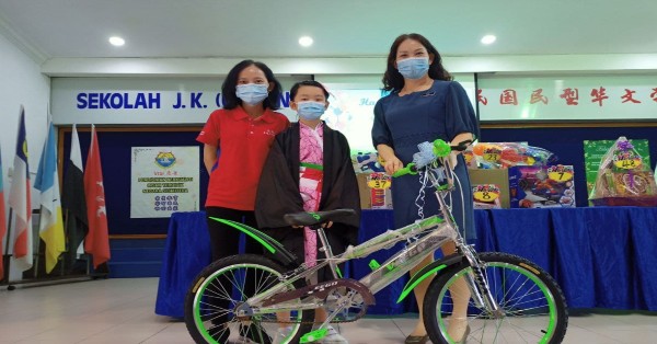 幸运学生曾子璇（中）在儿童节抽奖中，赢得一台脚车后，与级任老师江锦业（左）及校长丘月清分享喜悦。