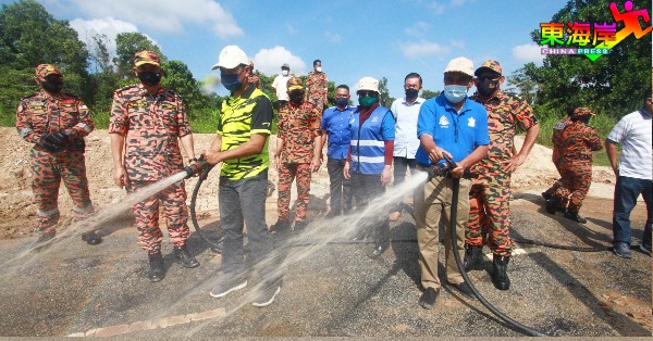 旺莫哈末(左2)在旁指导韩丹及拉欣慕达使用喷水泵清洗住宅区泥泞。