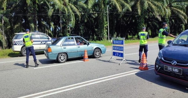 彭州陆路交通局执法官员在繁忙路段设路障，提醒公路使用者遵守条规。