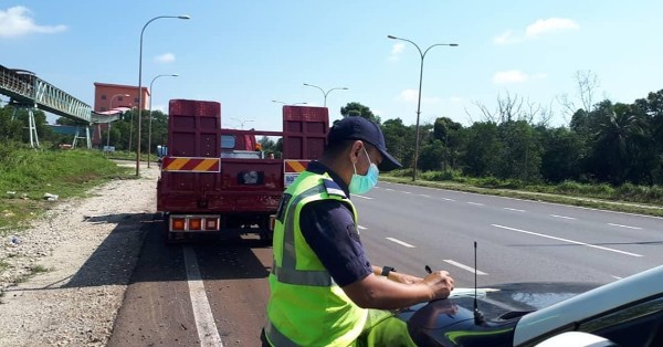 彭州陆路交通局执法官截查违例车辆后，当场开罚单。