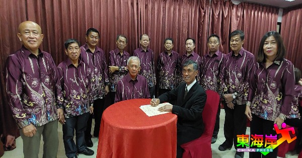 陶启顺（坐右）在陶启联（中）及理事见证下，为关丹琼崖公会新届理事会签署监誓书。