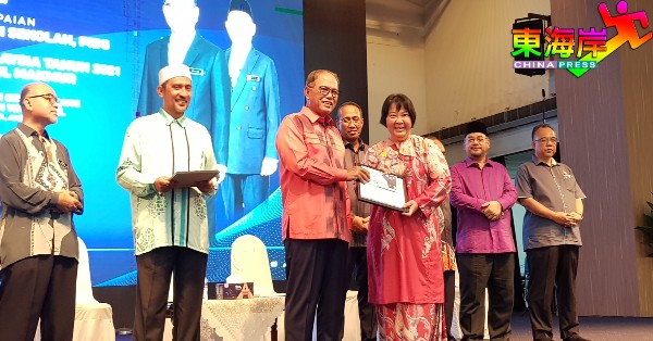 文达国中家教协会获选为优异家教协会之一，主席陈宝玉（右3）从旺罗斯迪手中接领奖励。