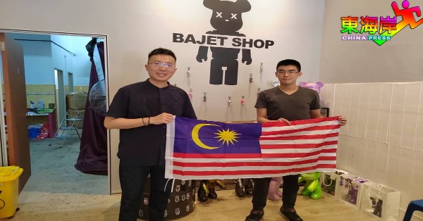 谢东成（左）移交国旗予华裔青年企业家。