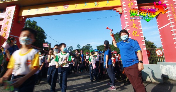 罗素君（右）为低年级国庆游行队伍主持鸣笛开走仪式。