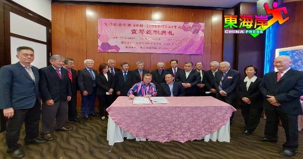 关丹积善堂新届理事成员见证黄崇洸（坐者左）为就职宣誓书署名。