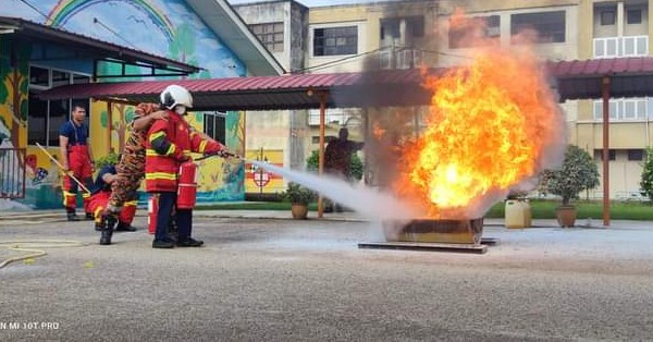 学生穿上指定防火装备后，在消拯员的指导政进行灭火。