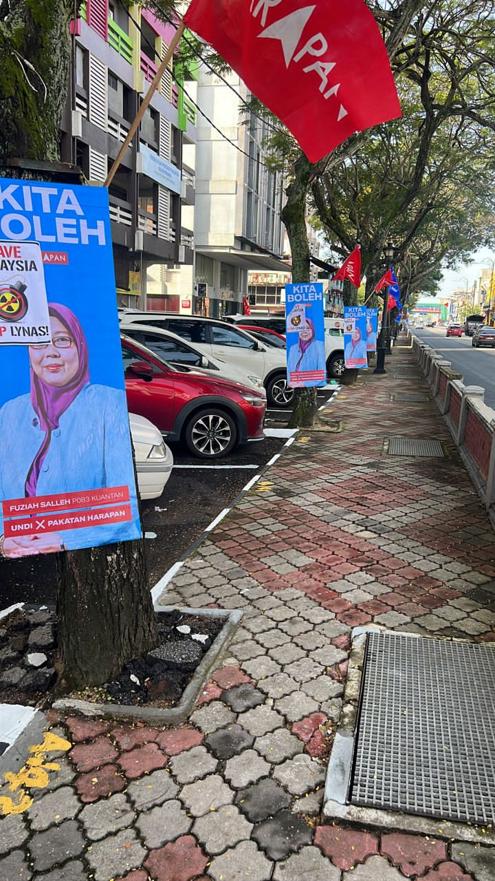 悬挂于关丹大街一带的傅芝雅竞选直幅海报遭人贴上“拯救大马，停止莱纳斯”口号标志贴纸。