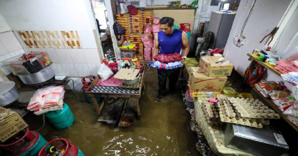 甘榜阿罗苏挠班江的食店东主莫哈末阿凡迪（37岁），尝试从洪水淹没的店铺中抢救部分粮食物资。