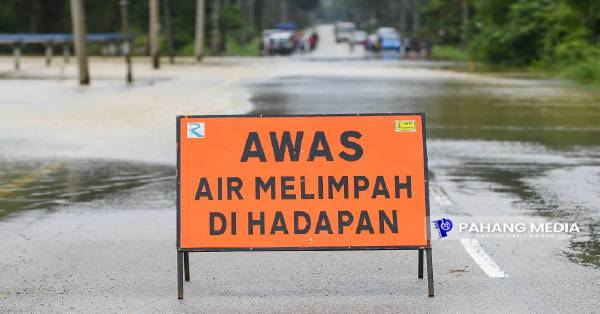 公共工程员在积水覆盖路面较宽的路段，置放积水泛滥警示牌。