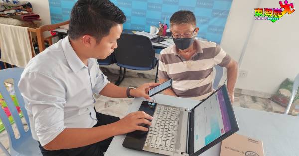 陈俊广（左）亲自为民众丘先辉注册PADU帐号，及更新个人和家庭资料。