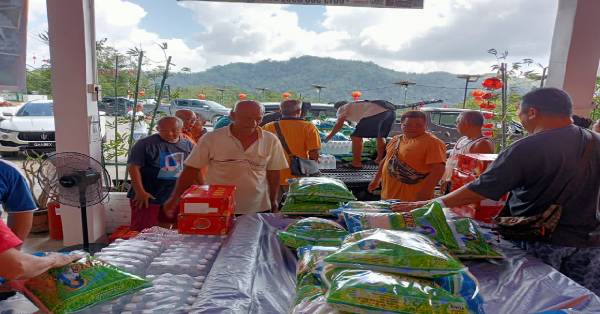 志工们分工合作将粮食物资重新包装，为沿户派送做好准备。