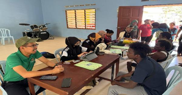 拉查曼利祖恩（左）亲自率队到立卑偏远原住民村，协助居民完成PADU登记时，与村民交流。