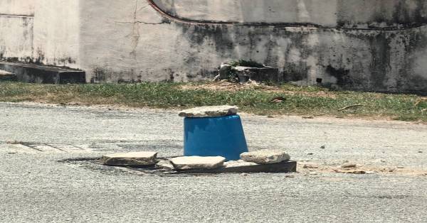塑料水桶被居民置放在被破坏的井盖处，以提醒来往公路使用者。
