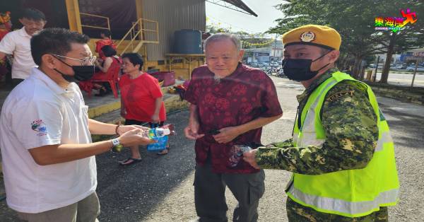 义工及志愿警卫员派发口罩、矿泉水面包予到场老者，并给予防疫叮嘱。